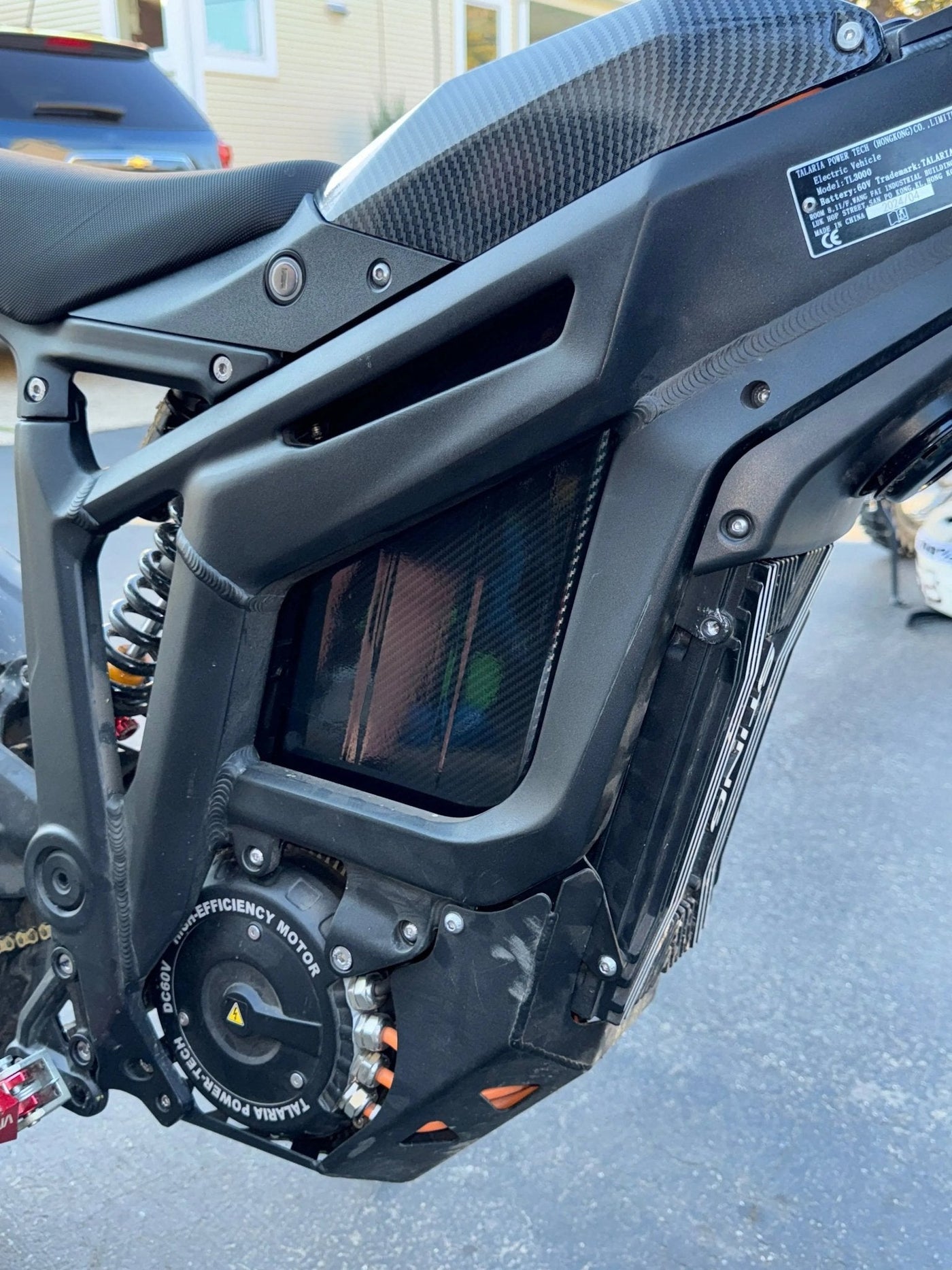 Carbon fiber battery wrap installed on e-moto battery in shade