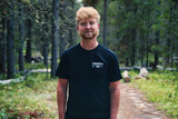 Rider facing the camera on a forest trail wearing the Smart Car Throttle Bros Tee