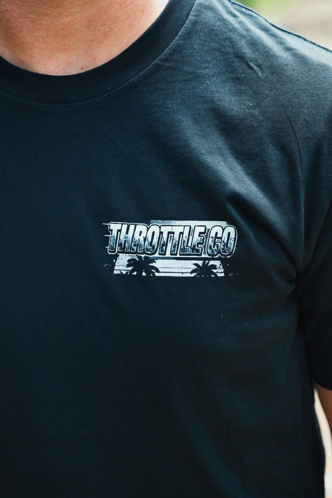 Close-up of the tonal THROTTLE CO chest print on the black Smart Car Throttle Bros Tee